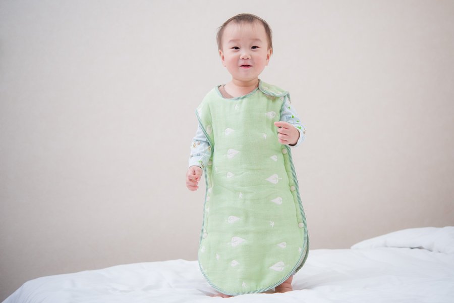 孩子穿著綠色六重紗防踢被,肩部與側邊按扣清楚可見
